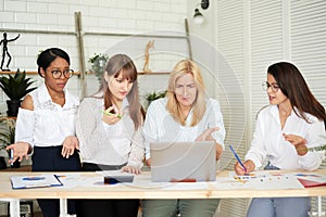 Serious female multiracial team solving problem together, diverse focused african, asian and caucasian colleagues