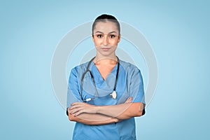 Serious female nurse with crossed arms in scrubs