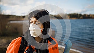 Serious female paramedic turns head and looks at you near blue lake