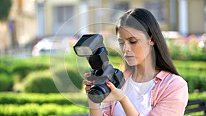 Serious female photographer checking settings on camera, technique problems