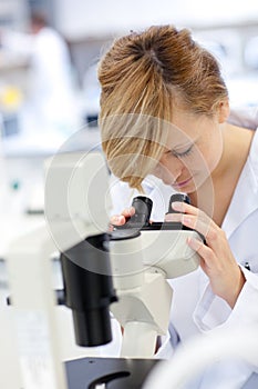 Serious female scientist using a microscope