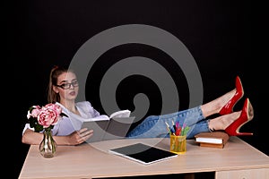 Serious female teacher with her red shoes on the table.