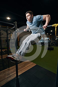 Serious fit young man pulling himself up on horizontal bar