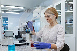 Serious and focused female researcher working with microscope inside laboratory, mature and experienced scientist