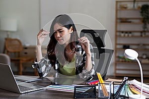 Serious and focused graphic designer sitting at her desk, surrounded by sketches and drawings