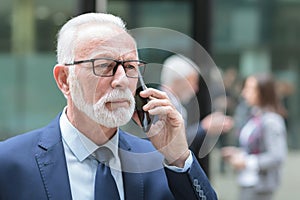 Serious, focused senior businessman talking on the phone, receiving bad news
