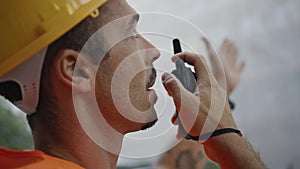 Serious foreman speaking wireless communicator at downtown closeup. Man uniform photo