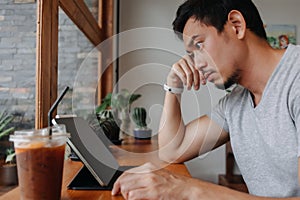 Serious freelance man working in the cafe with his tablet computer.