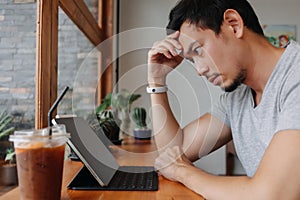 Serious freelance man working in the cafe with his tablet computer.