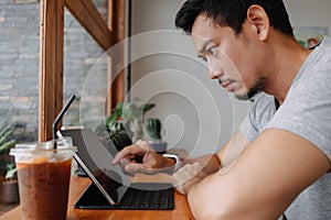 Serious freelance man working in the cafe with his tablet computer.