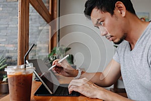 Serious freelance man working in the cafe with his tablet computer.