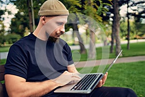 Serious freelancer sits in outdoors while typing text working on laptop. 5G internet connection