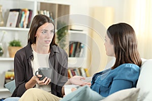 Serious friends talking at home on a couch