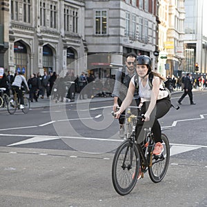 serious girl in a blue dress with polka dots crossing the road on a bicycle