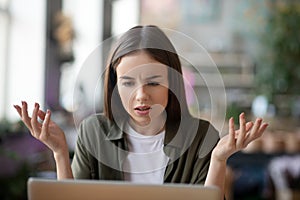 Serious girl looking at a laptop screen with a frowning eyebrow.