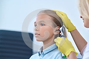 Serious girl of school age examined by otolaryngologist