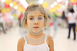 Serious girl standing in big store alone