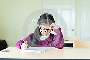 Serious girl writing on a blank paper in classroom