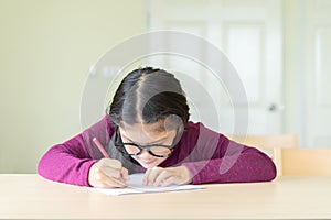 Serious girl writing on a paper in classroom