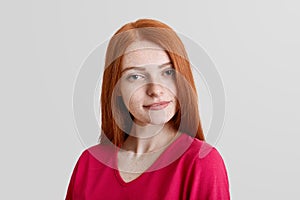 Serious good looking freckled young female model, has freckles on face, long straight red hair, dressed casually, looks with myste