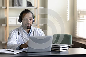 Serious GP doctor in headphones engaged in online virtual consultation