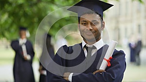 Serious graduate crossing arms with diploma in hand, completion of studies pride