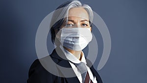 Serious graying businesswoman in mask. Close up portrait of caucasian middle-aged looking at camera. Text space on both