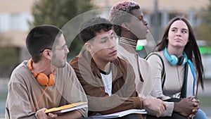 Serious group of students sitting and chatting relaxed together outdoors