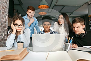 Serious groupmates working on project in front of laptop