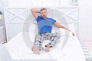 Serious guy in cozy pajamas resting in bed in morning, wakeup