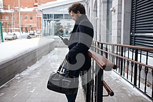 Serious handsome awesome man texting with friends on mobile phone at city street