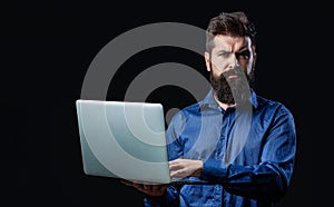 Serious handsome bearded man worker laptop. Bearded male businessman holding a computer in his hands isolated on black