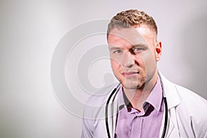 Serious handsome male doctor wearing white lab coat looking at camera