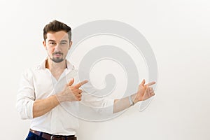 Serious handsome man standing while presenting against white background. Young handsome businessman with beaming smile pointing wi