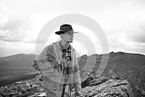 Serious handsome pensive male hiker on a top of a mountain