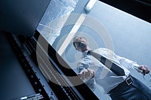 Serious handsome technician checking the network server