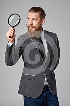 Serious hipster business man with magnifying glass