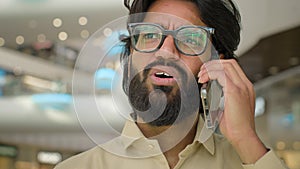 Serious Hispanic Indian businessman executive in glasses Arabian bearded man talking mobile phone smartphone business