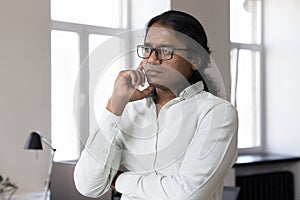 Serious Indian businessman looking into distance thinks over project