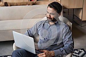 Serious indian businessman working on laptop computer from home office.