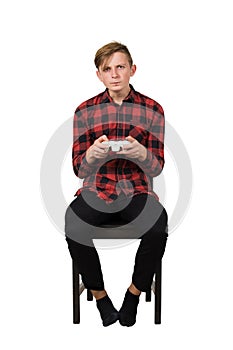 Serious intent teen guy seated on chair playing video games isolated over white background. Boy stand all ears holding joystick photo