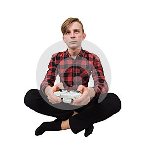 Serious intent teen guy seated on the floor playing video games isolated over white background. Boy stand all ears holding