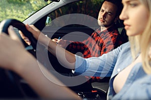 Serious lady and instructor in car, driving school