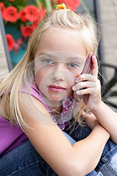 Serious little blond girl talking on a cellphone