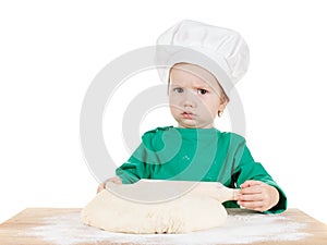 Serious little boy kneading dough for the cookies, isolated on white