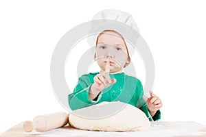 Serious little boy kneading dough for the cookies, isolated on white