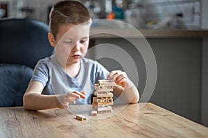 Serious little boy playing board game with wooden turret