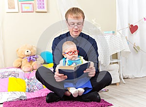 Serious little boy read an old book with his father in glasses