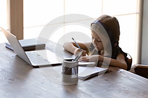 Serious little gen Z kid in earphones studying from home photo