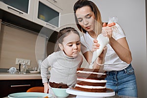 Serious little girl and her sisiter preparing cake for their mother